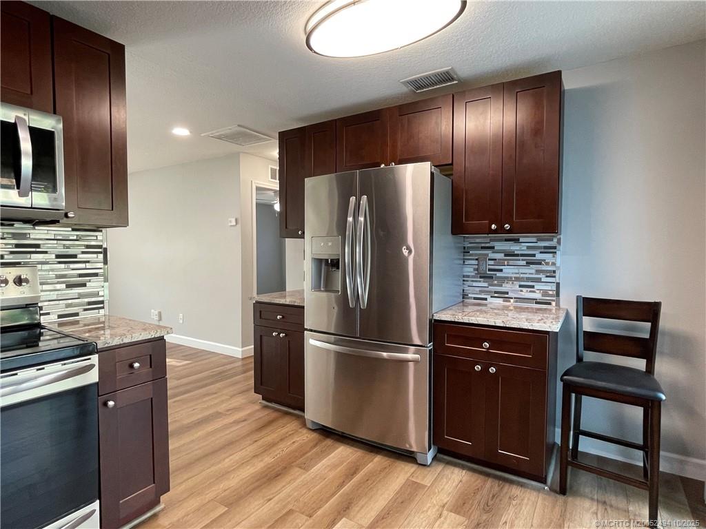 406 Robalo Court Stuart, FL 34996 - Photo 8 of 22 a kitchen with granite countertop stainless steel appliances and wooden cabinets