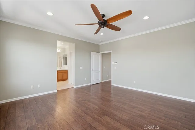 a view of an empty room with wooden floor and a ceiling fan