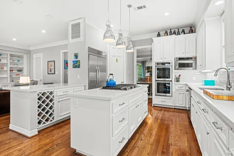a large kitchen with stainless steel appliances a white stove top oven a sink a chimney and a center island
