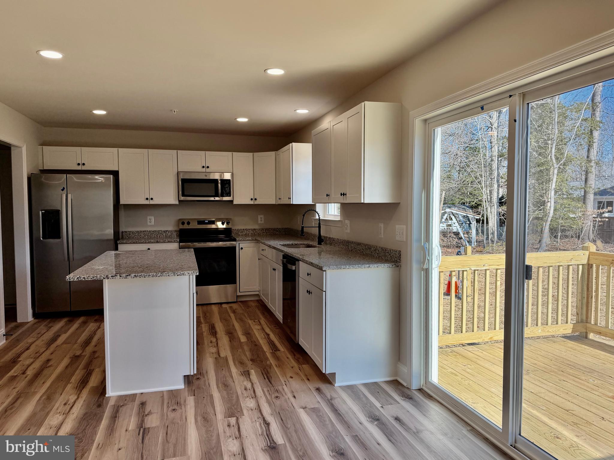 613 Santa Fe Trail Lusby, MD 20657 - Photo 6 of 24 a kitchen with kitchen island granite countertop a stove a sink a refrigerator with grey cabinets and wooden floor