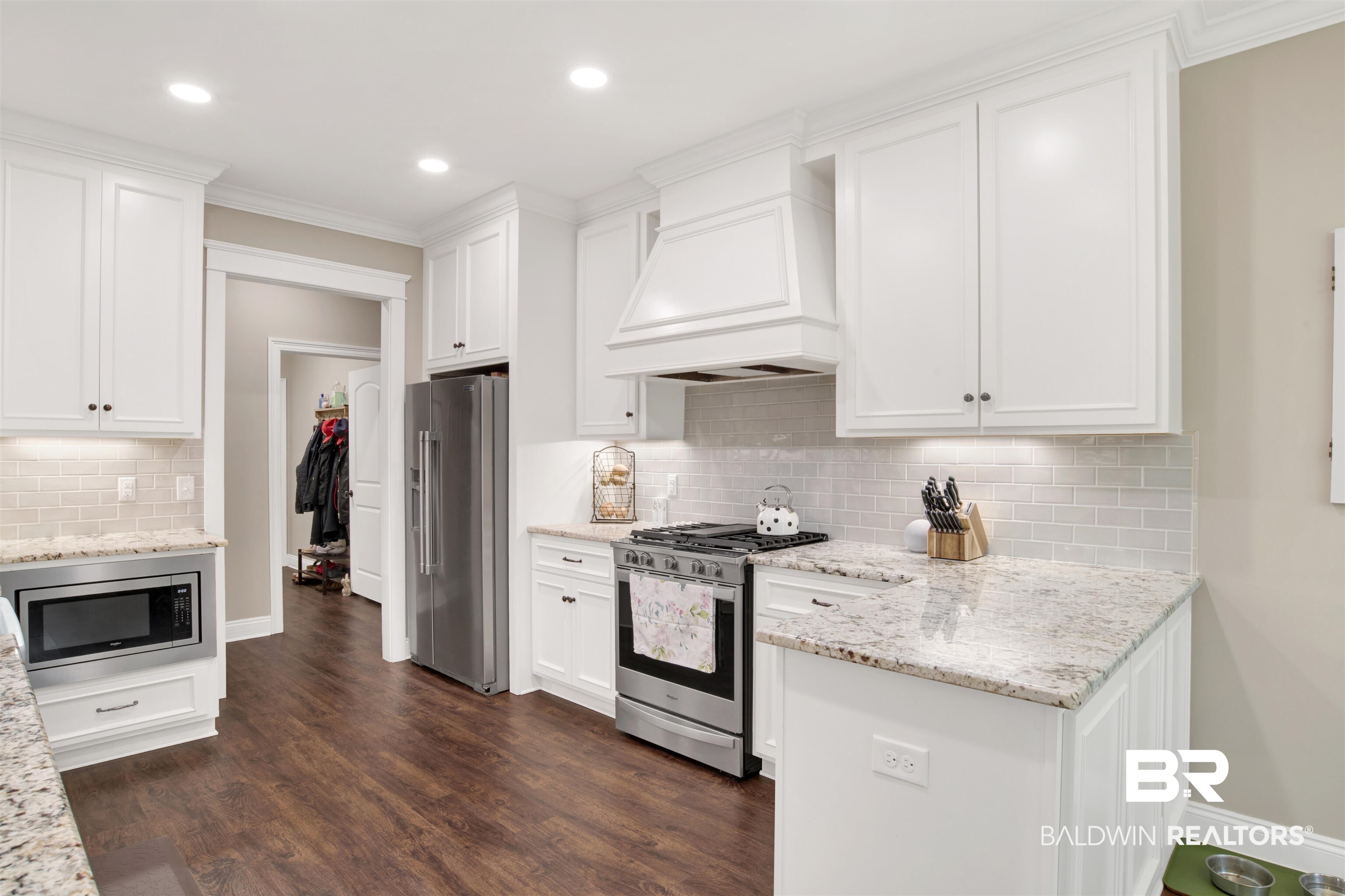 2440 Johnson Road West Mobile, AL 36695 - Photo 14 of 40 Kitchen featuring appliances with stainless steel finishes, dark hardwood / wood-style flooring, premium range hood, tasteful backsplash, and white cabinetry