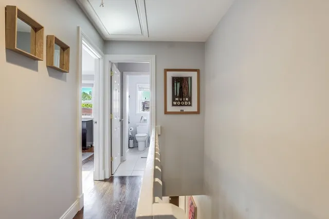 a view of a hallway with wooden floor and a bathroom