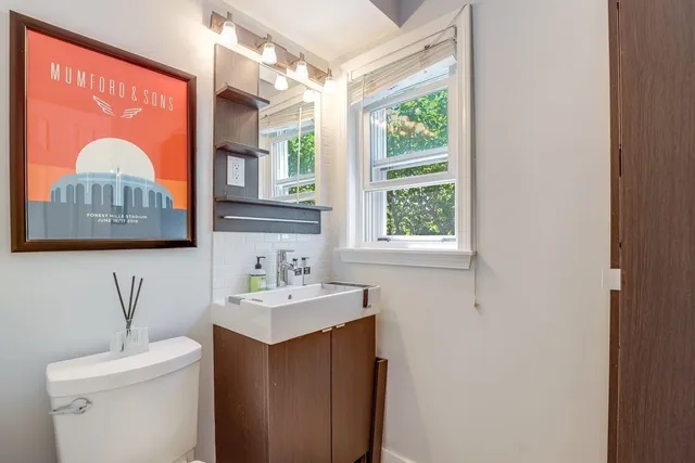 a bathroom with a sink toilet vanity and window