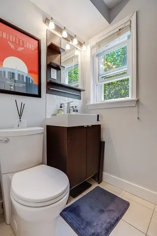 a bathroom with a toilet a sink a window and mirror