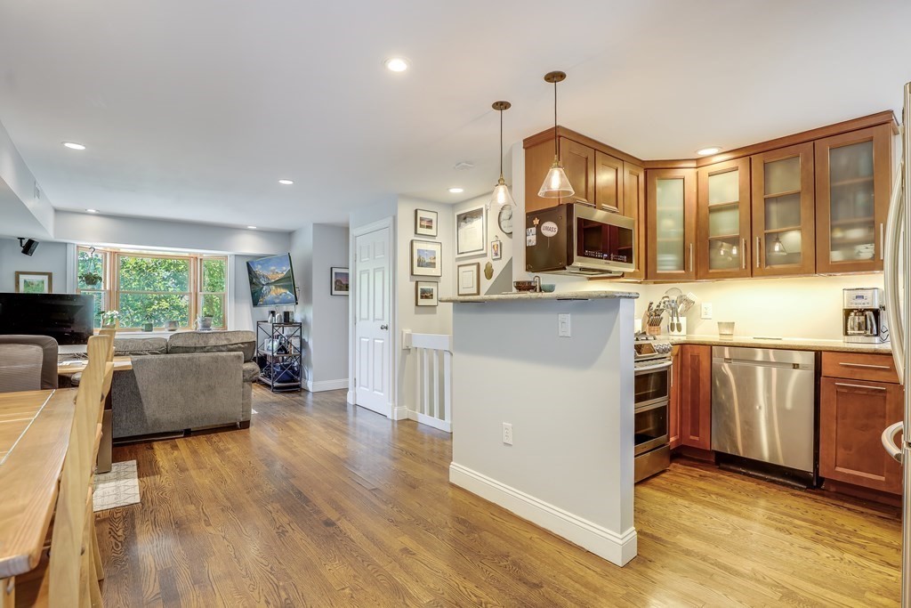 154 West 3rd Street, Unit 154 Boston, MA 02127 - Photo 10 of 26 a kitchen with kitchen island granite countertop a stove top oven a sink dishwasher and a fireplace with wooden floor
