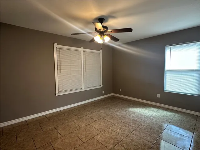 a view of an empty room and window and chandelier fan