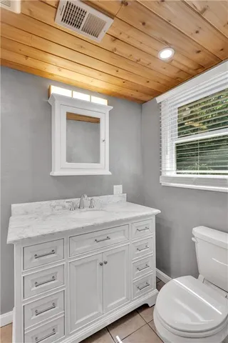 a bathroom with a granite countertop toilet sink and mirror