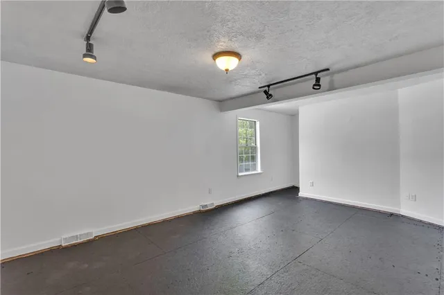 an empty room with windows and fan