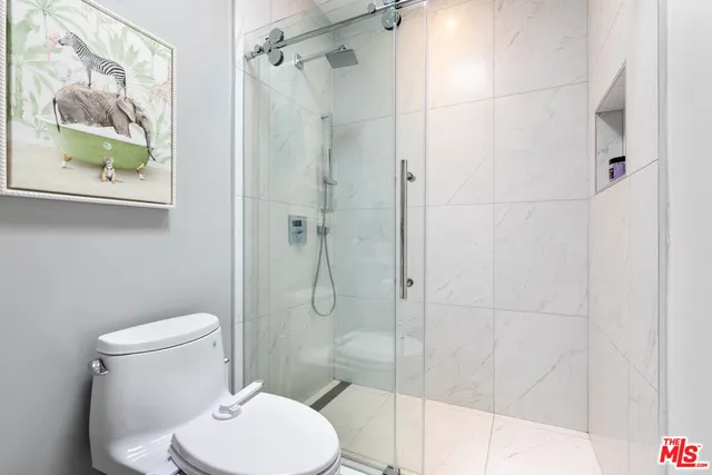 a white toilet sitting next to a bathroom shower