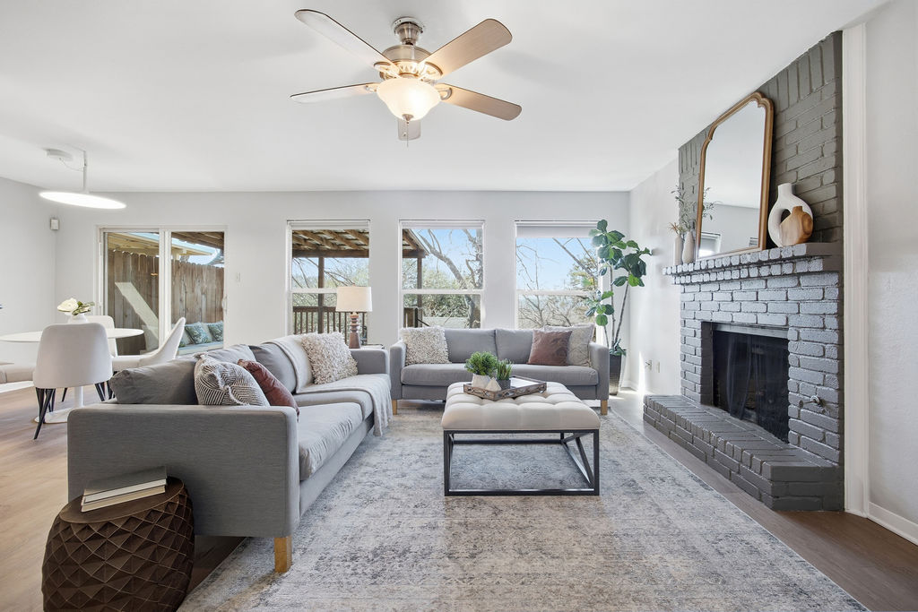 Living room featuring wood finished floors, ceiling fan, a fireplace, and healthy amount of natural light