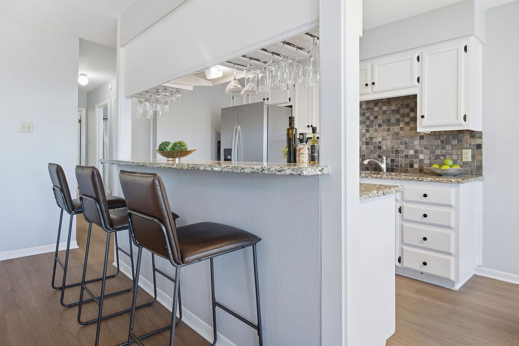 6486 Hart Lane Austin, TX 78731 - Photo 6 of 28 Kitchen featuring a kitchen bar, white cabinets, light stone counters, and light wood-type flooring