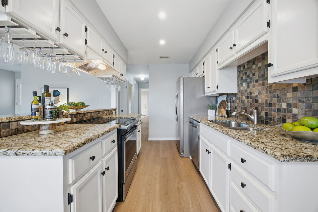 6486 Hart Lane Austin, TX 78731 - Photo 8 of 28 Kitchen with white cabinetry, stainless steel appliances, and light stone countertops