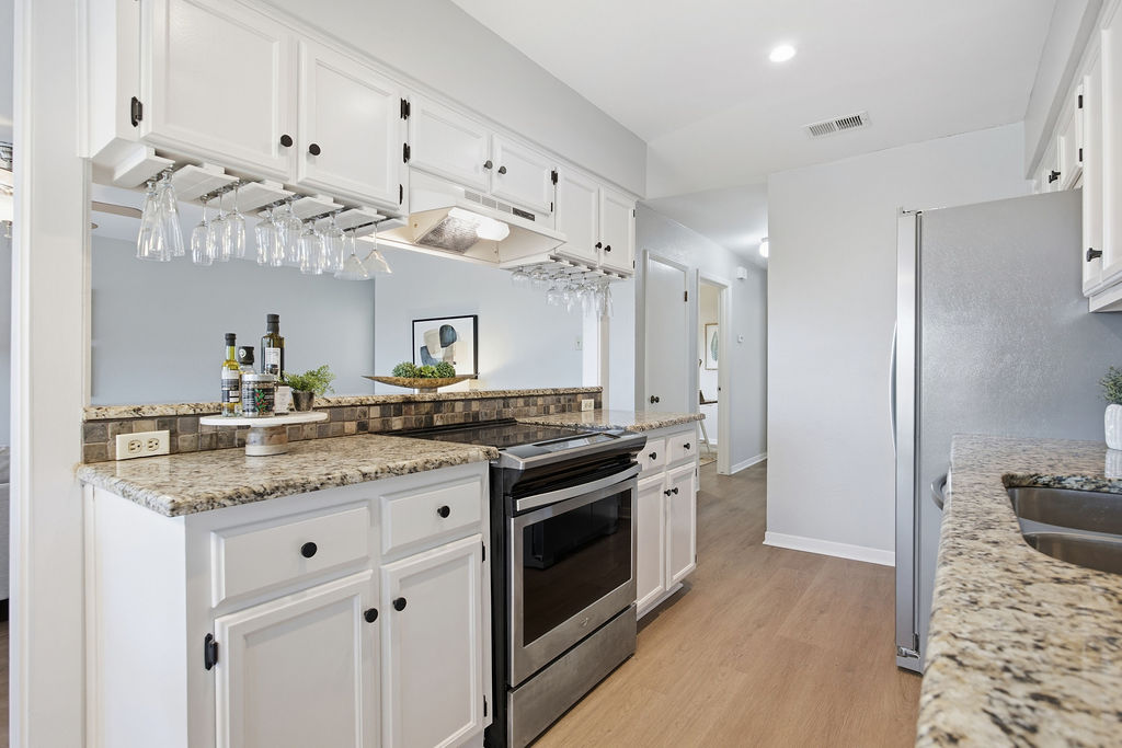 6486 Hart Lane Austin, TX 78731 - Photo 9 of 28 Kitchen with stainless steel appliances, white cabinets, light stone counters, light wood finished floors, and recessed lighting