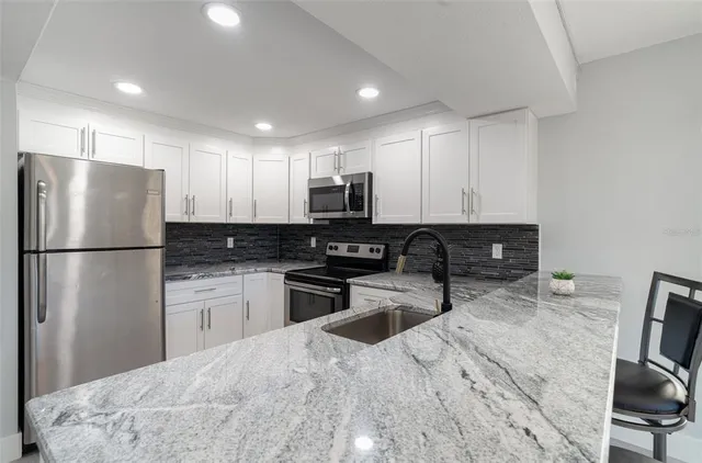 a kitchen with granite countertop a refrigerator and a sink