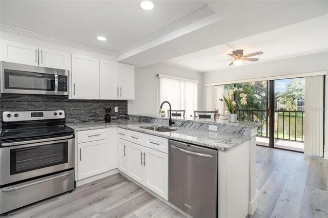 a kitchen with stainless steel appliances granite countertop a stove a sink and a microwave