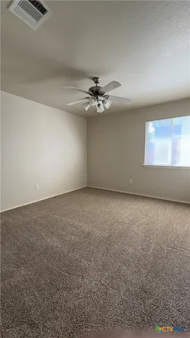 an empty room with windows and fan