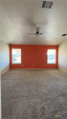 an empty room with windows and fan