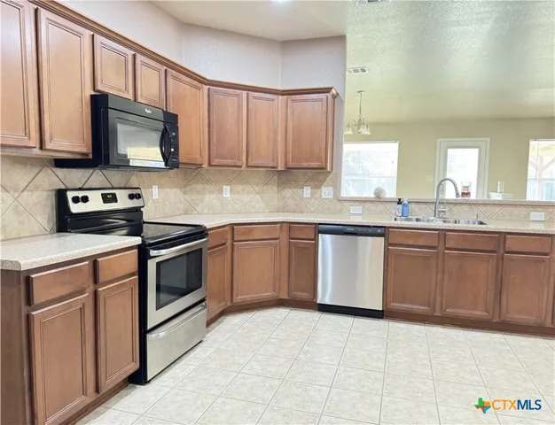 a kitchen with stainless steel appliances granite countertop a stove a sink and a microwave