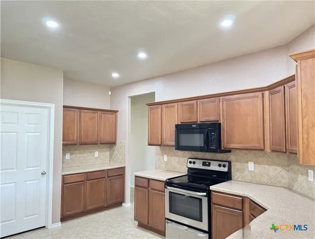 a kitchen with granite countertop a stove a sink and a microwave