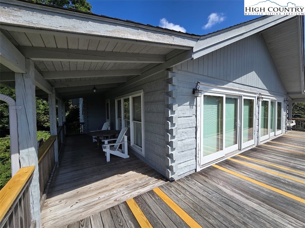 979 Wagon Road Warrensville, NC 28693 - Photo 6 of 50 a view of a patio with table and chairs with wooden floor and floor to ceiling window