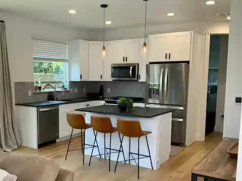 a kitchen with stainless steel appliances granite countertop a stove a sink a refrigerator a microwave and a refrigerator