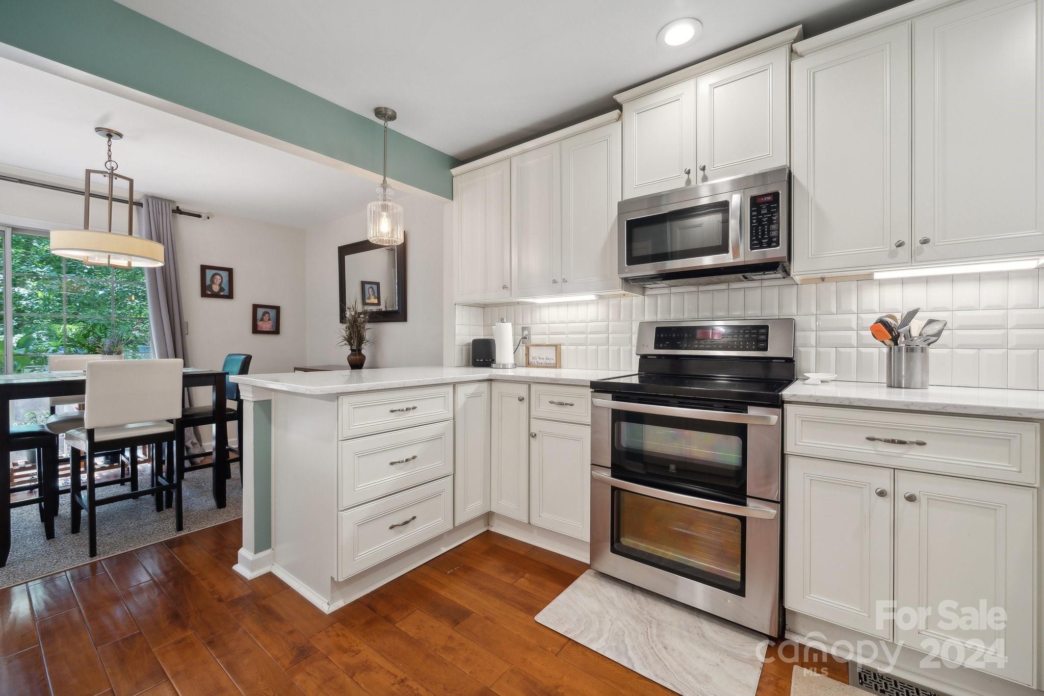 9012 St Thomas Lane Charlotte, NC 28277 - Photo 7 of 25 a kitchen with white cabinets stainless steel appliances and wooden floor