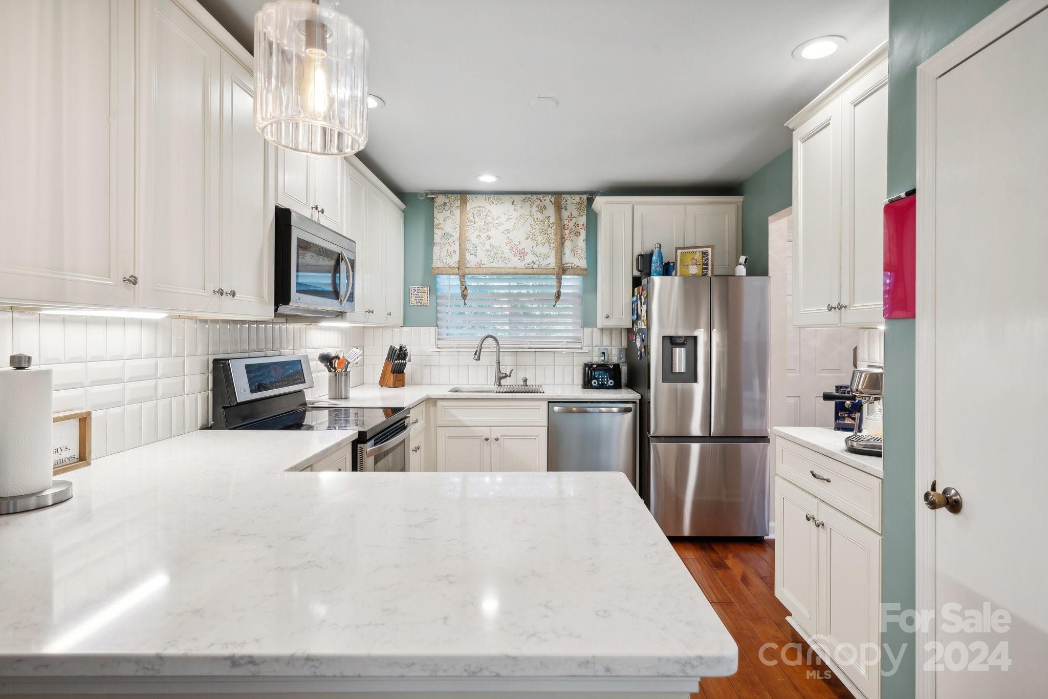 9012 St Thomas Lane Charlotte, NC 28277 - Photo 9 of 25 a kitchen with stainless steel appliances kitchen island granite countertop a refrigerator oven a sink dishwasher and white cabinets with wooden floor