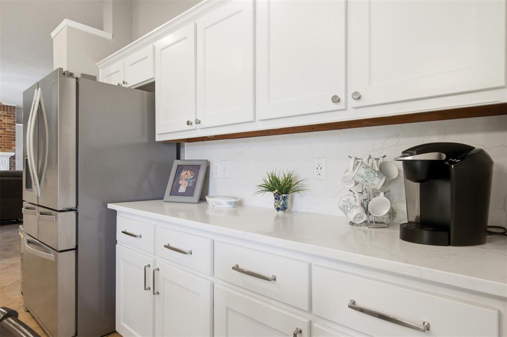 4218 Glistening Spring Rowlett, TX 75088 - Photo 15 of 39 White cabinetry with brushed nickel hardware, light-toned countertops, and a full-height backsplash