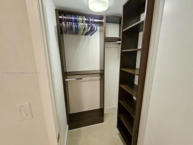 a view of walk in closet with clothes and shoes