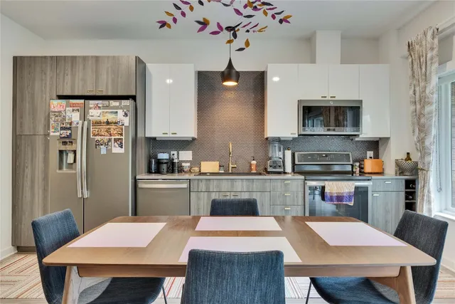 a kitchen with a refrigerator a stove a sink a dining table and chairs