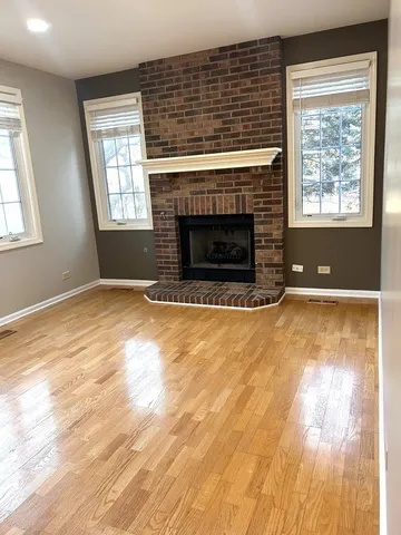 a view of empty room with wooden floor and fireplace