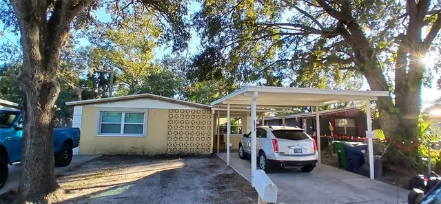 a view of a house with a barbeque and a large tree