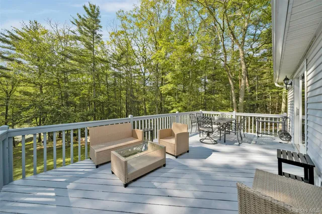 a view of a patio with couches table and chairs under an umbrella with wooden floor