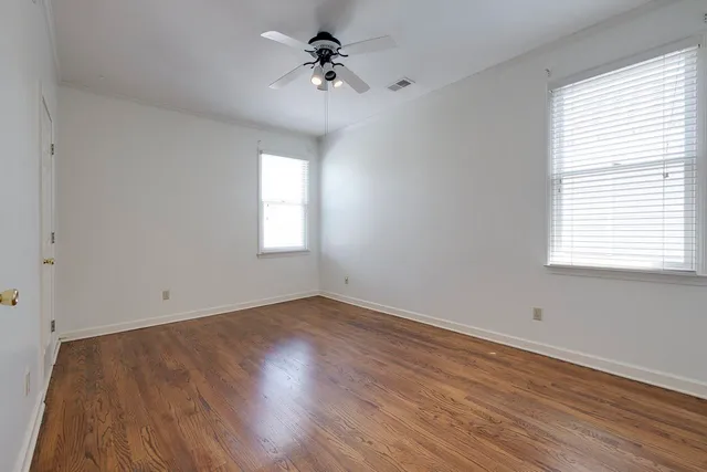 a view of empty room with wooden floor and fan
