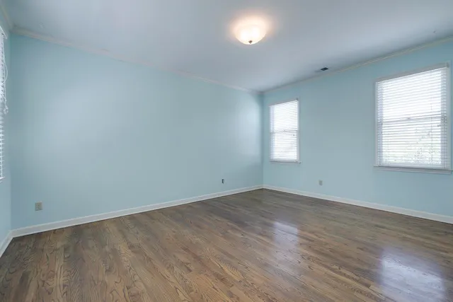 an empty room with wooden floor and window