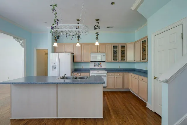 a kitchen with kitchen island granite countertop wooden cabinets and white appliances