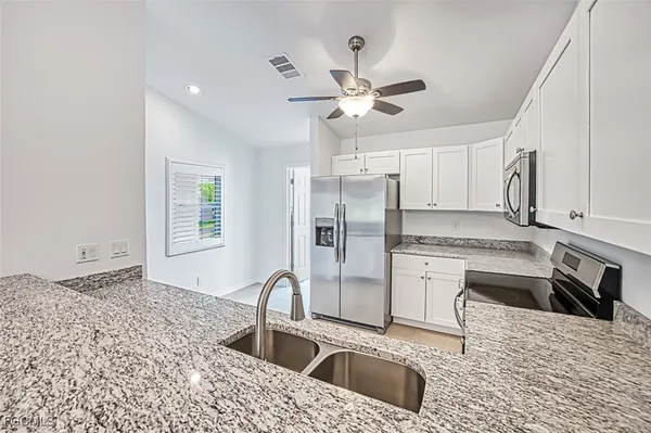 a kitchen with stainless steel appliances kitchen island granite countertop a sink refrigerator and cabinets