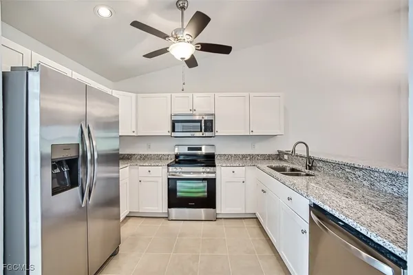 a kitchen with stainless steel appliances granite countertop a sink a stove and a refrigerator
