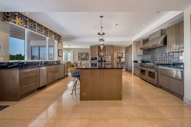 a large kitchen with stainless steel appliances kitchen island granite countertop a large counter top a stove a chimney a sink and cabinets