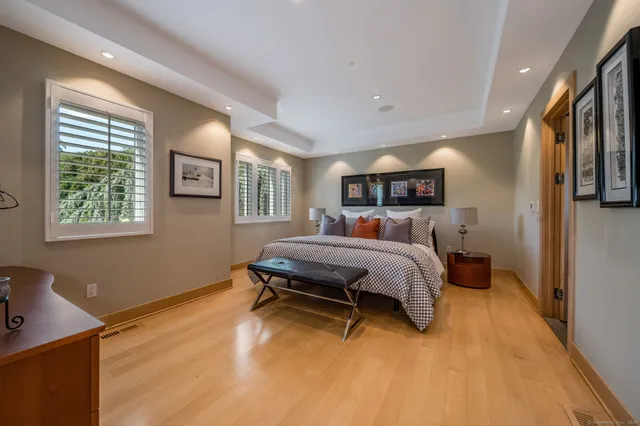 a bedroom with a bed large mirror and a window