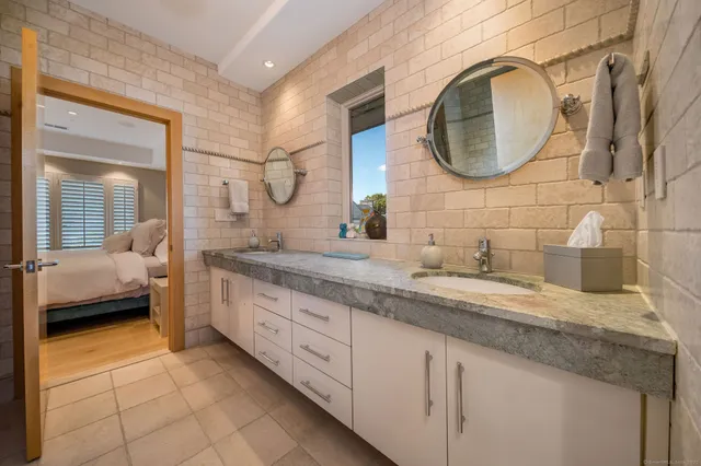 a en suite bathroom with a granite countertop double vanity sink and a mirror