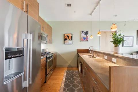 a kitchen with stainless steel appliances granite countertop a refrigerator a stove and a sink with wooden floor