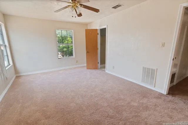 an empty room with a window and a ceiling fan