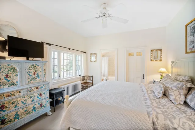 a bedroom with a bed a flat screen tv and a window