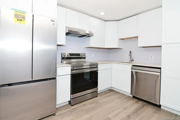 a kitchen with stainless steel appliances a sink a stove a refrigerator and cabinets