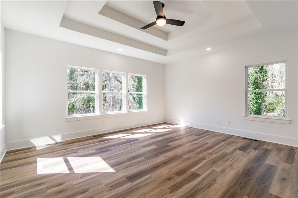 6121 Timberidge Drive Gainesville, GA 30506 - Photo 19 of 44 an empty room with wooden floor chandelier fan and windows