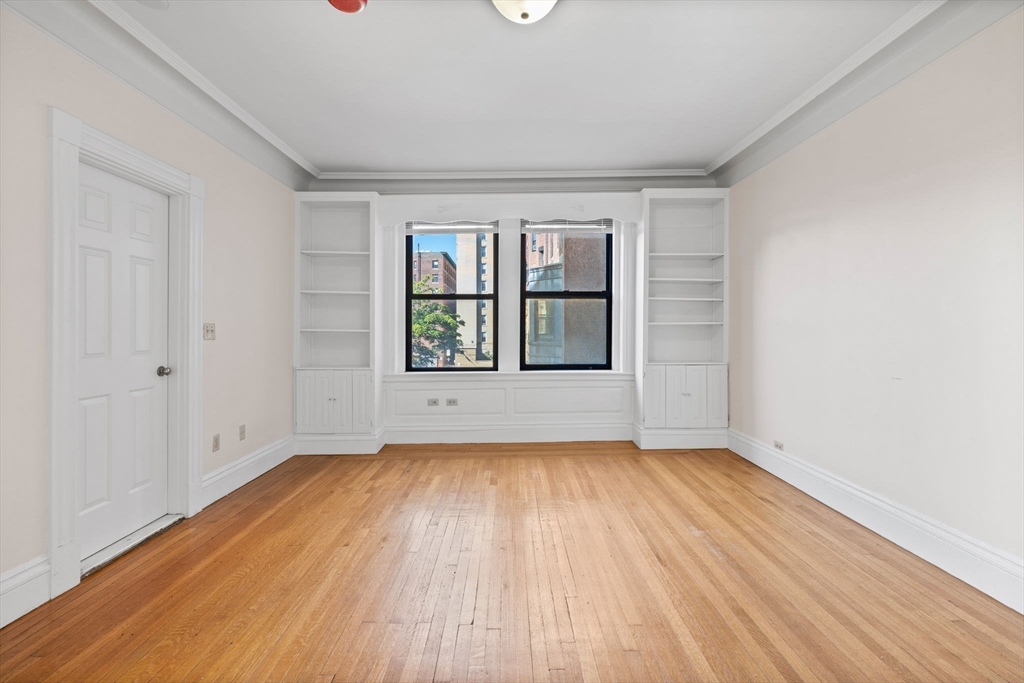 466 Commonwealth Avenue, Unit 305 Boston, MA 02215 - Photo 4 of 14 an empty room with wooden floor and windows