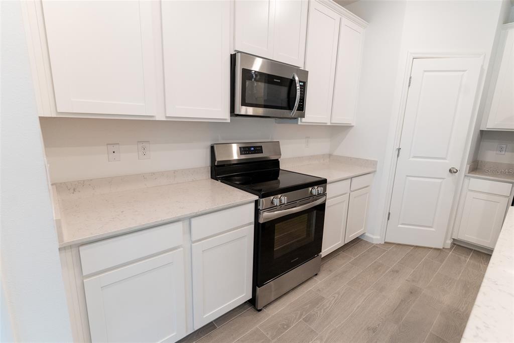 4501 Northwest 14th Loop Ocala, FL 34482 - Photo 22 of 38 a kitchen with granite countertop white cabinets and black appliances