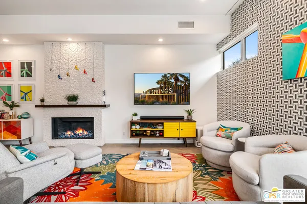 a living room with furniture and a fireplace with wine table