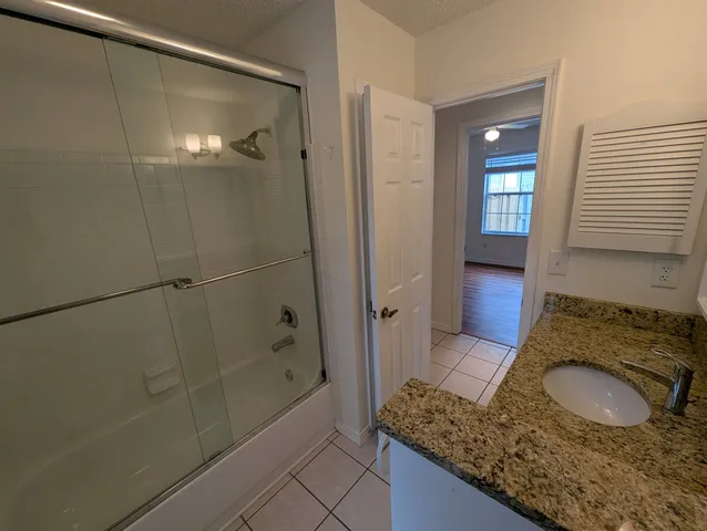 a bathroom with a granite countertop sink a mirror and shower